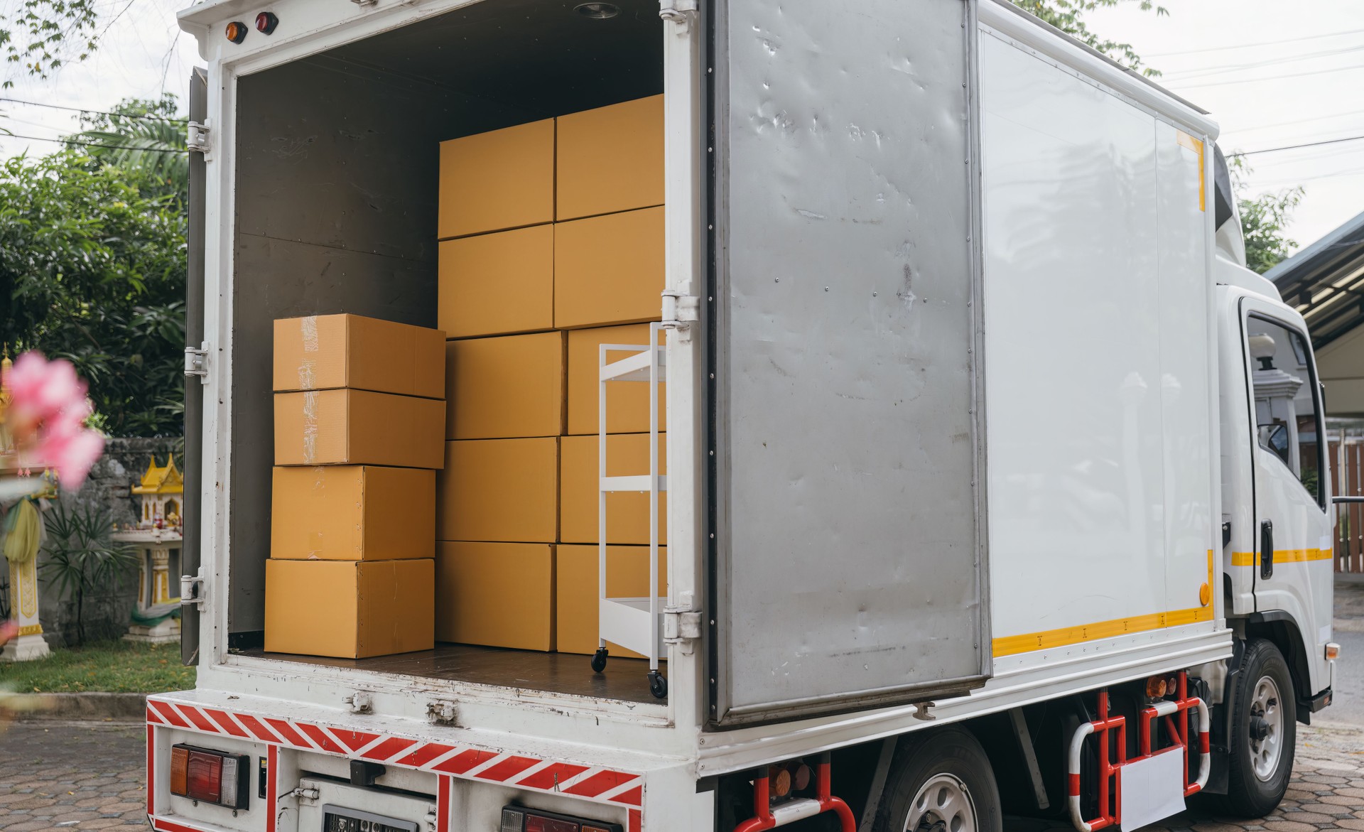 Outdoor scene, White delivery van and open car trunk carrying cardboard boxes. Logistic service for transporting items. House relocation. Moving Day Concept.