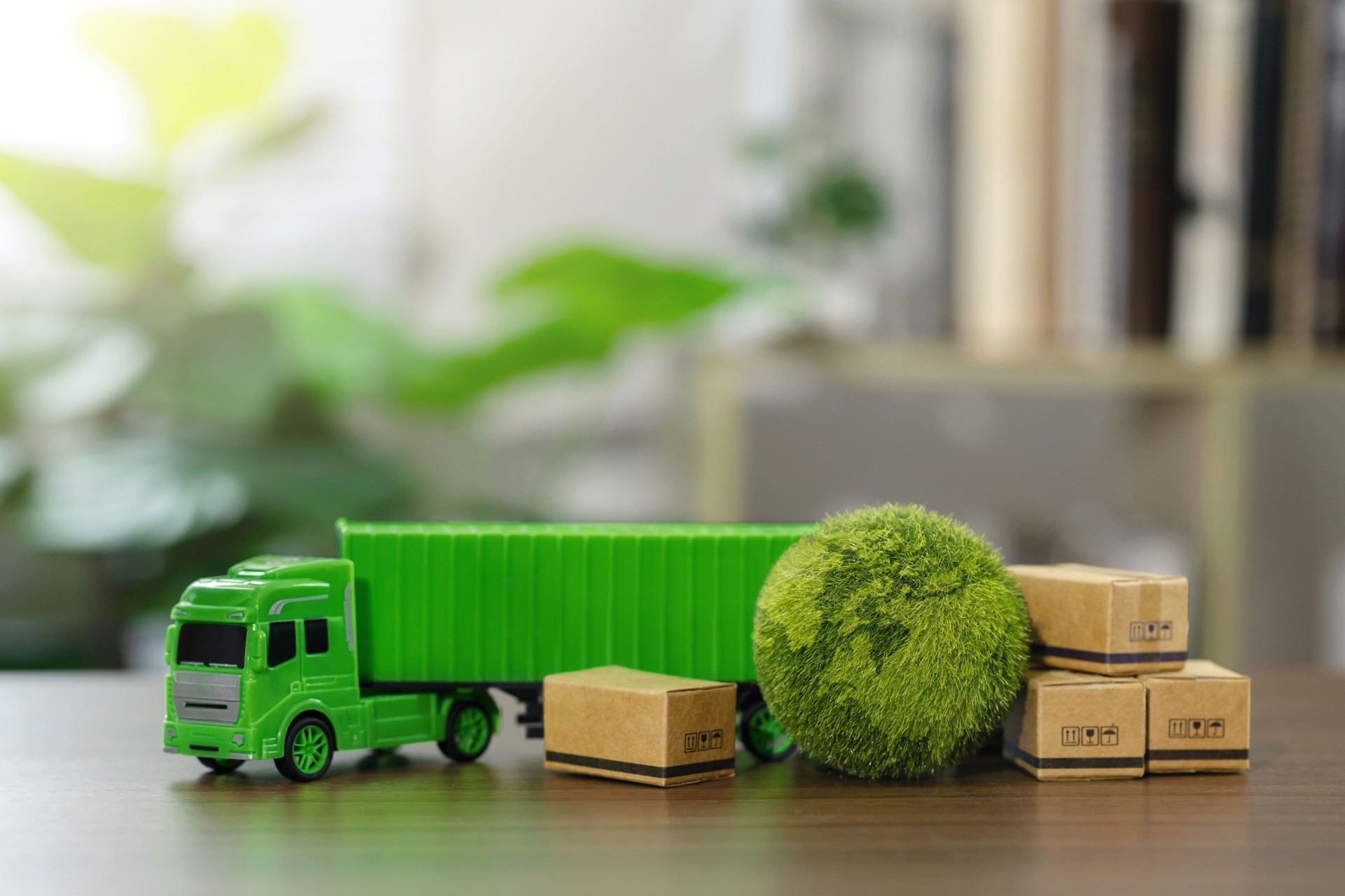 Green logistics and Sustainable global transport. Sustainable logistics.Green container trucks and parcels with eco-friendly packaging and the green world on the desk. Clean energy transportation.