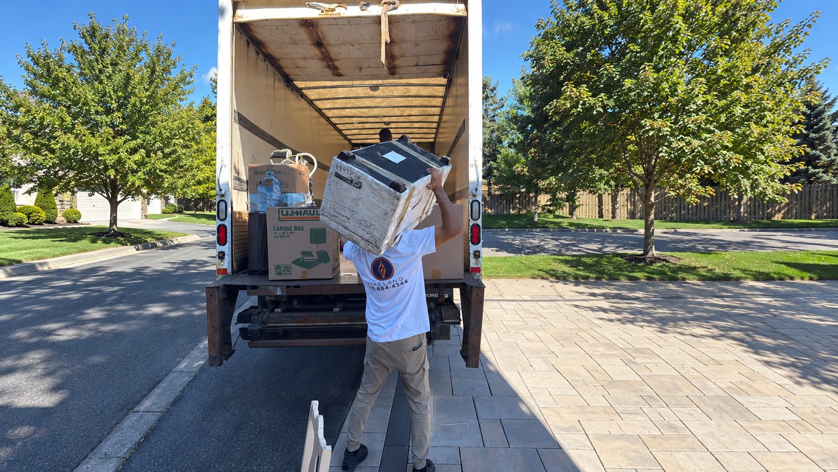 Fireland mover loading boxes into the back of a moving truck in a driveway
