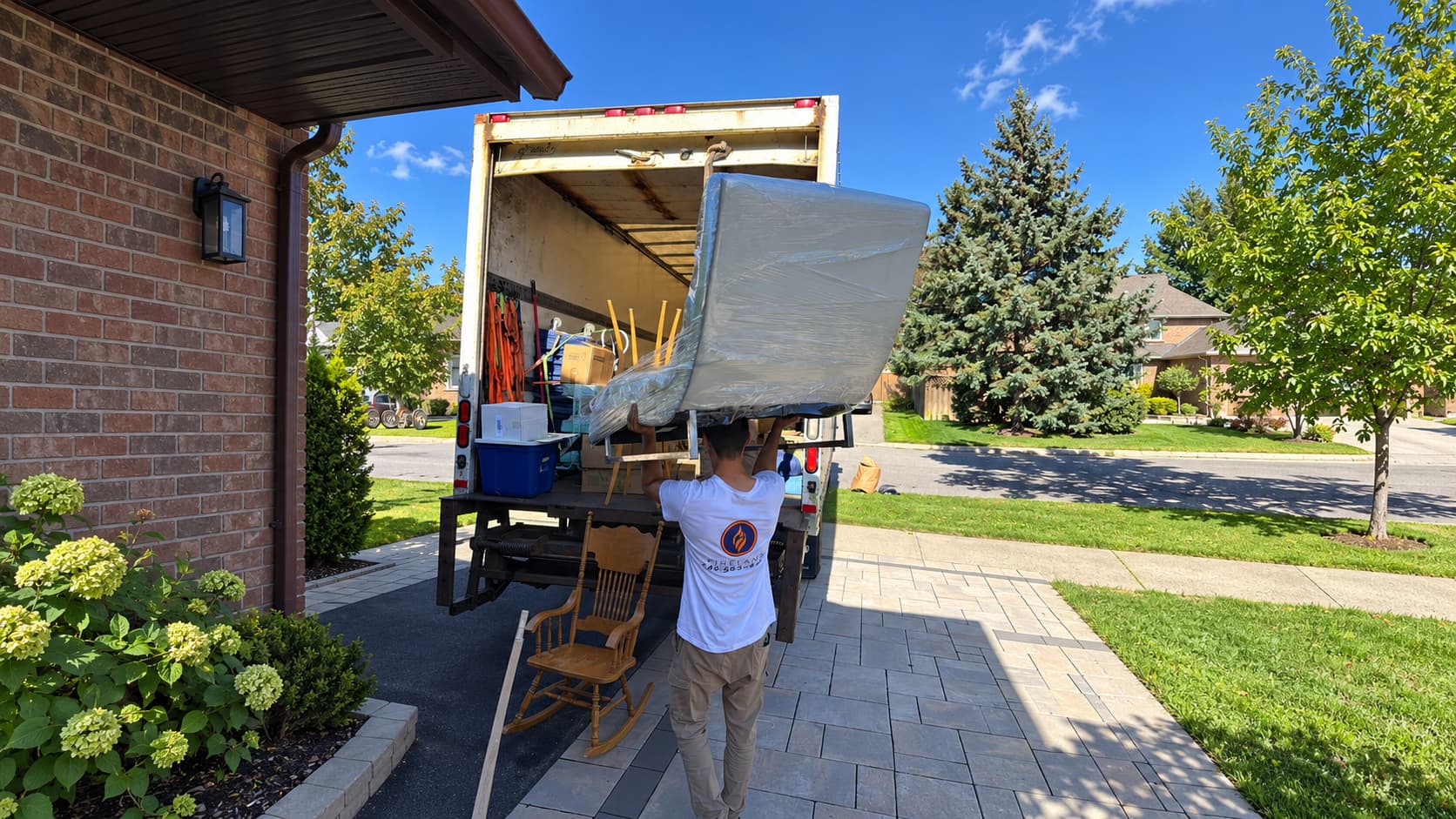 Fireland mover carrying furniture overhead into a moving truck on a sunny day