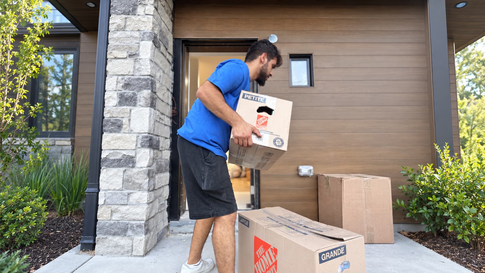 Fireland mover stacking moving boxes at the front door of a modern home